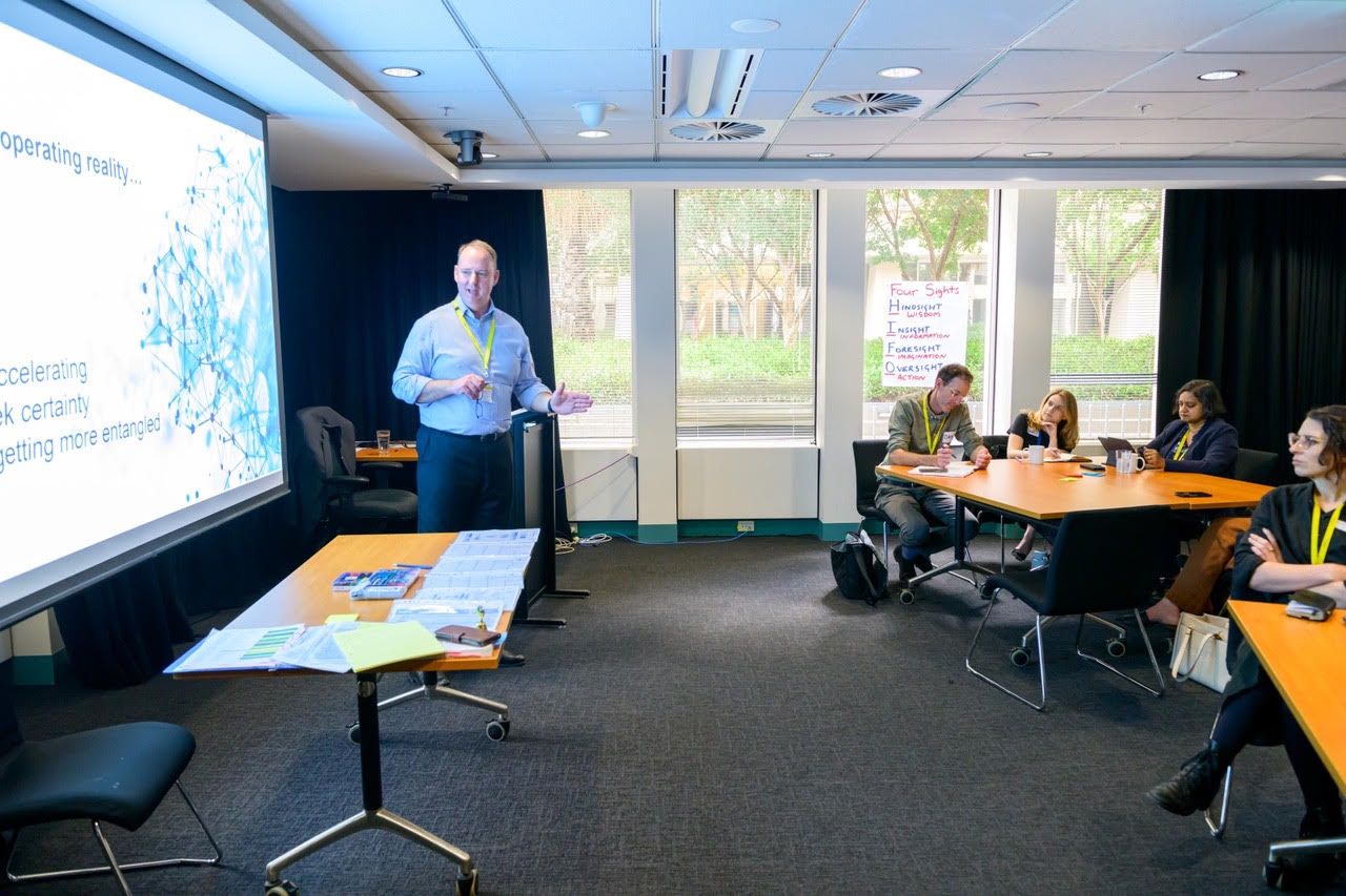 Rob Warner in a workshop room beside a wall chart of the four sights