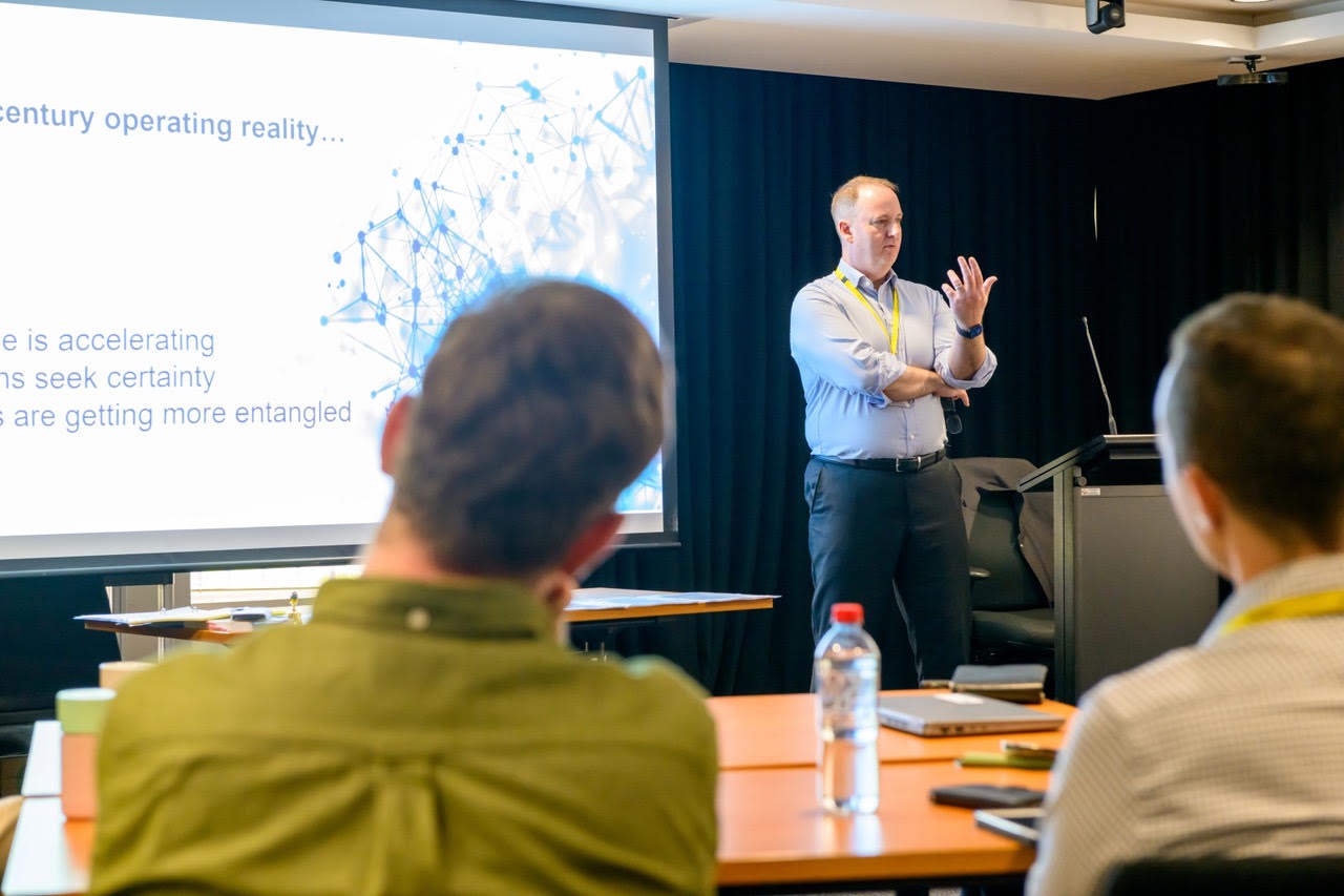 Rob Warner leading a session at the front of a room of regulatory staff.